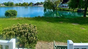Ein See mit einer Rasenfläche, einem weißen Zaun und einem Gebäude im Hintergrund.
