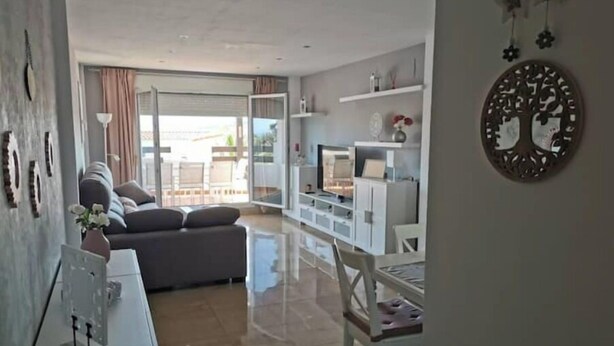Una sala de estar moderna con un sofá, televisor y un comedor con una silla.