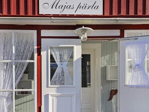 A building with a sign reading 'Majas pärla' above a white door with lace curtains. - 5 Star Holiday Home in Unnaryd (Unnaryd)