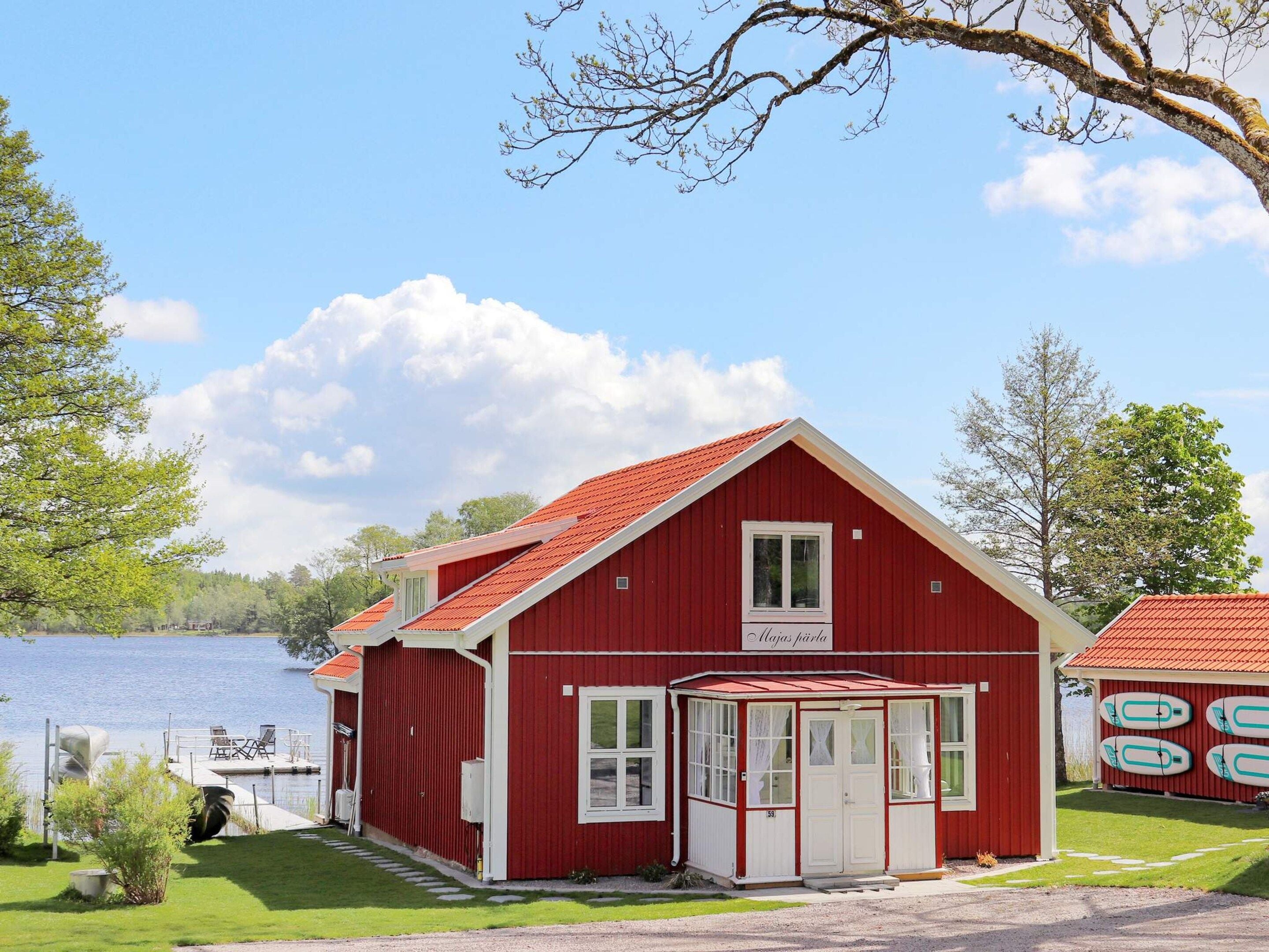 A red building with a white door and windows, a covered porch, and a lake in the background.