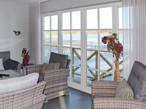 A room with wicker furniture, a bed, and a view of a body of water through large windows. - 5 Star Holiday Home in Unnaryd (Unnaryd)