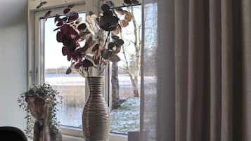 A vase with dried leaves on a windowsill.