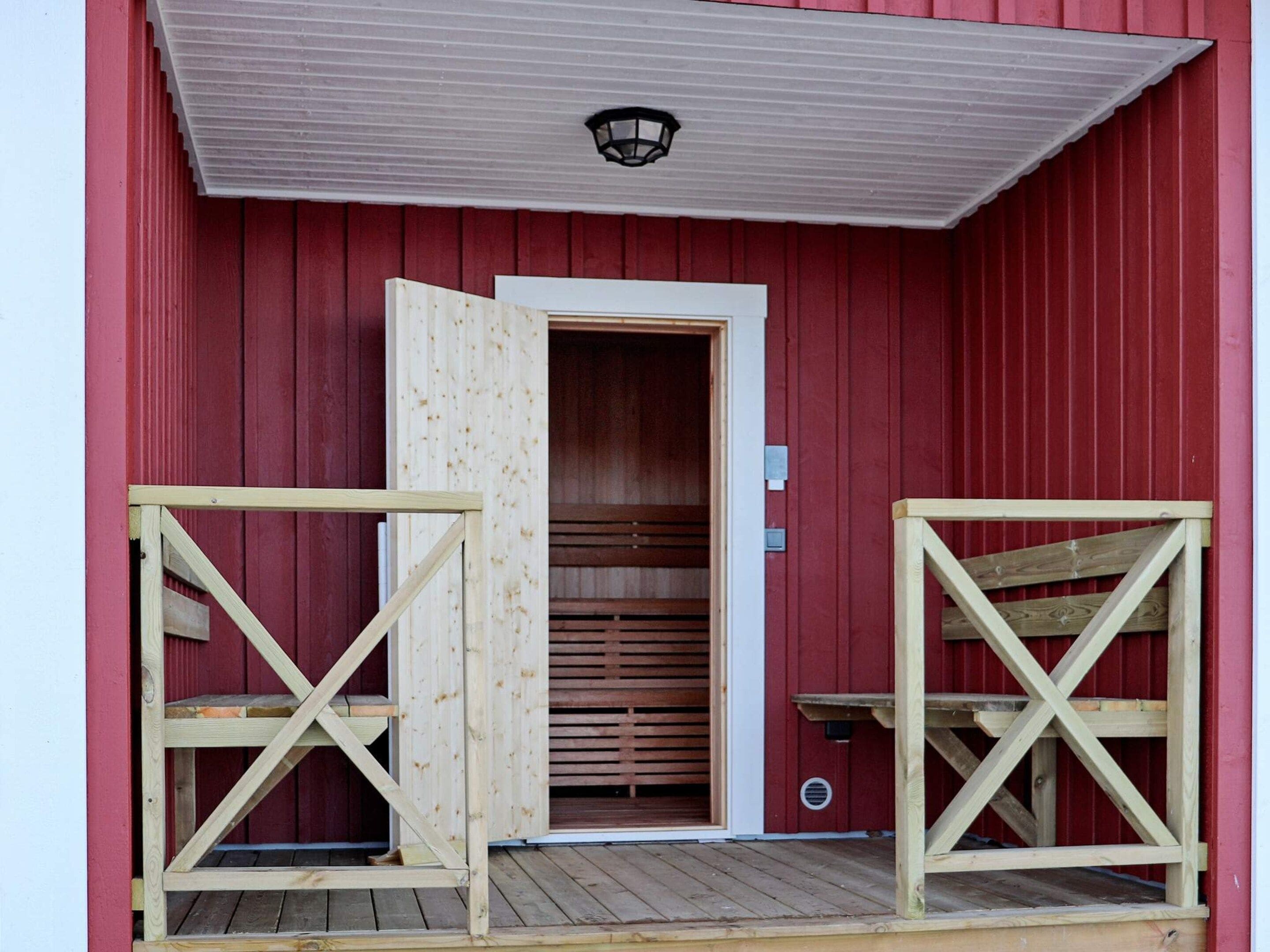 A red barn with a wooden door and a small porch area.