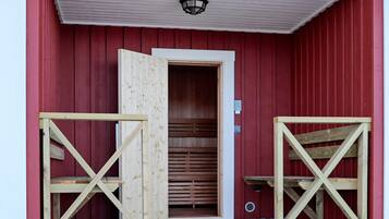 A red barn with a wooden door and a small porch area.