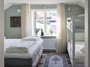 A bedroom with a bunk bed, a single bed, a window with curtains, a radiator, and a rug. - 5 Star Holiday Home in Unnaryd (Unnaryd)