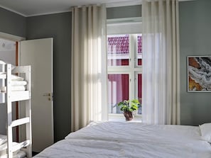 A bedroom with a bunk bed, a single bed, a window with curtains, a potted plant, and a painting on the wall. - 5 Star Holiday Home in Unnaryd (Unnaryd)