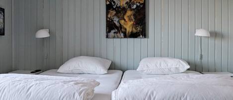A room with two beds, each with white bedding and pillows, and a single painting on the wall.