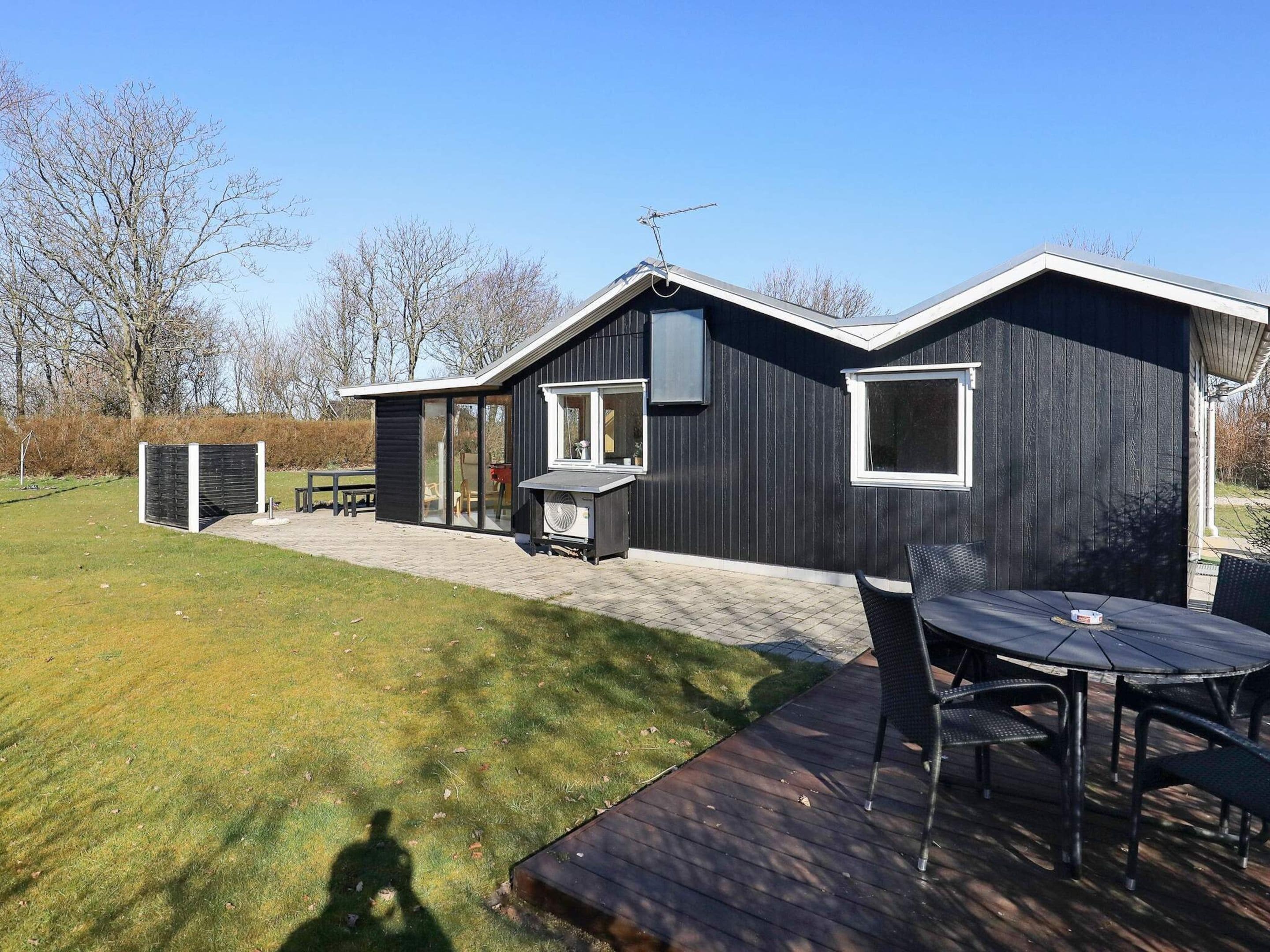 A modern house with a patio area, a table, and chairs.