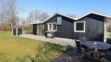 A modern house with a patio area, a table, and chairs.