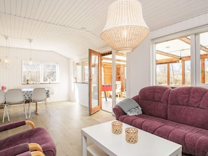 A modern living room with a purple sofa, a white coffee table, and a large chandelier.