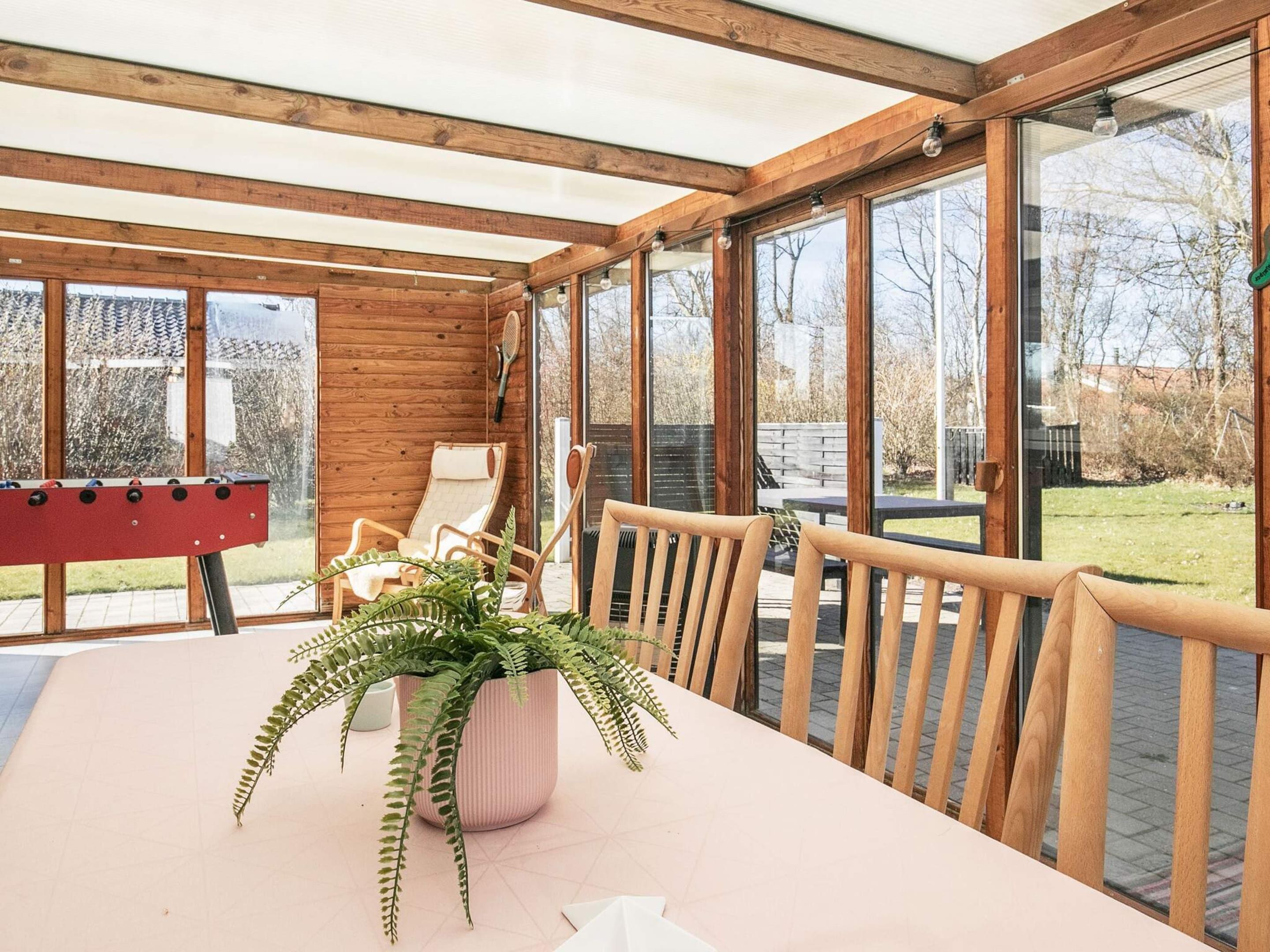 Una sala de estar con ventanales, una mesa, sillas y una mesa de futbolín.