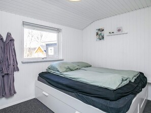 A bedroom with a single bed, a window, a wall-mounted shelf with two items, and a door. - 4 Star Holiday Home in Vinderup (Vinderup)