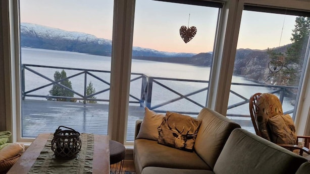 En hyggelig stue med udsigt over en sø og bjerge.