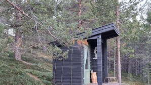 En hytte med en lille veranda, et vindue med gardin og en træbænk.