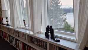 En reol med bøger og en kikkert på et vindueskar.