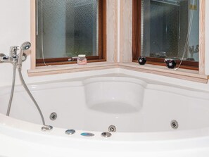 A corner bathtub with a window, a showerhead, and a small jar on the windowsill. - 6 Person Holiday Home in Laeso-by Traum (Læsø)