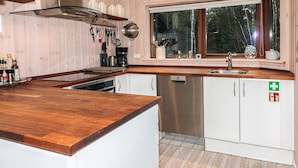 A modern kitchen with wooden cabinets, a stainless steel sink, and a window overlooking a forest. - 6 Person Holiday Home in Laeso-by Traum (Læsø)