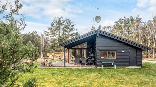A cabin with a covered patio, a satellite dish, and a view of the surrounding forest. - 6 Person Holiday Home in Laeso-by Traum (Læsø)
