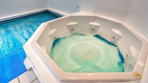 A hot tub with a blue pool adjacent to it.