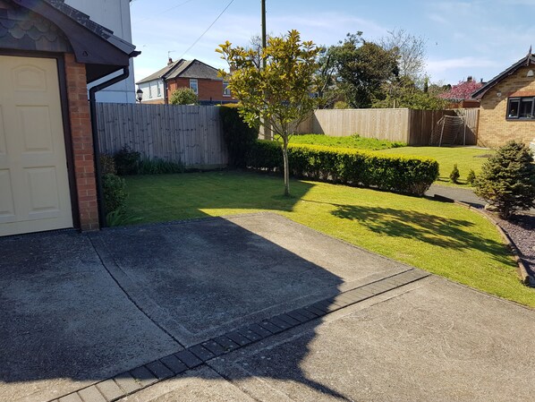A residential driveway leading to a garage, surrounded by a well-maintained lawn and a wooden fence. - 5 minute walk to beach, quite cul-de-sac location, parking for 3 cars (Sandown)