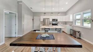 Una cocina moderna con armarios blancos, electrodomésticos de acero inoxidable e iluminación colgante.