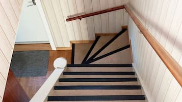 A staircase with a wooden handrail and a carpeted landing.