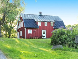 A red wooden house with a sloped roof, a front porch, and a small garden area. - 7 Person Holiday Home in Oxaback (Öxabäck)
