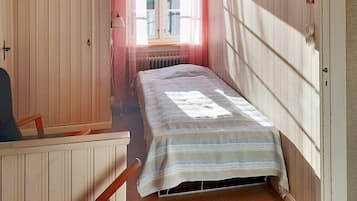 A narrow room with a single bed, a chair, and a radiator.