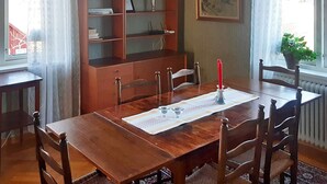 Ein Esszimmer mit Holztisch, Stühlen, einem Bücherregal und einem Gemälde an der Wand.
