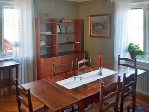 A dining room with a wooden table, chairs, a bookshelf, and a painting on the wall. - 7 Person Holiday Home in Oxaback (Öxabäck)
