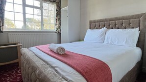 A neatly made bed with white and pink linens, a tufted headboard, and a window with floral curtains. - Unwind in Comfort at Cosy Caradus Free Parking (Birmingham)