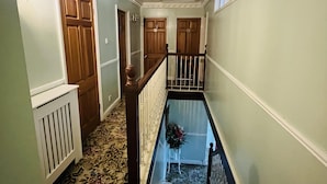 A hallway with a patterned carpet, wooden doors, and a white radiator. - Unwind in Comfort at Cosy Caradus Free Parking (Birmingham)