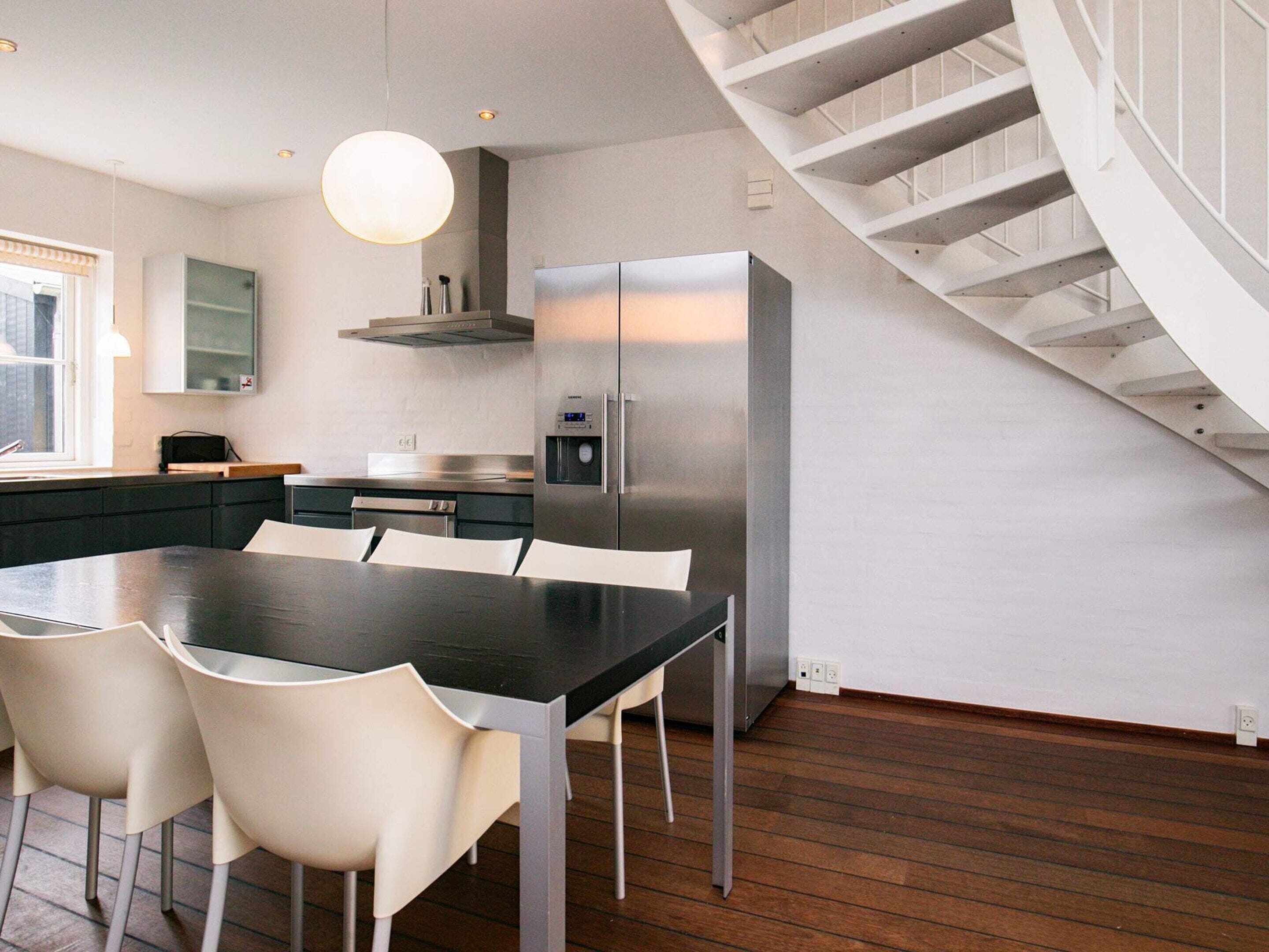 A modern kitchen with a central island, stainless steel appliances, and a spiral staircase.