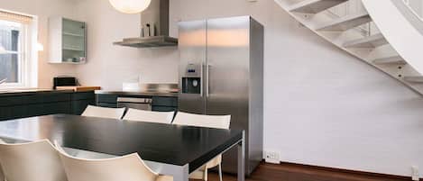 A modern kitchen with a central island, stainless steel appliances, and a spiral staircase.