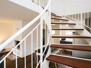 A modern interior with a spiral staircase, wooden flooring, and a dining area with chairs and a table.