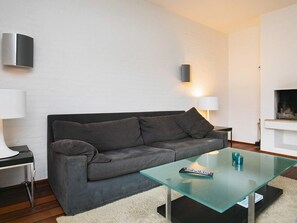 A modern living room with a grey sofa, a glass coffee table, and a fireplace. - 4 Star Holiday Home in Skagen (Skagen)