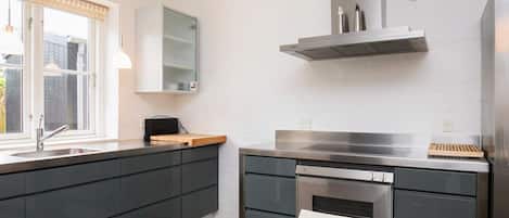 Una cocina moderna con horno empotrado, campana extractora de acero inoxidable y ventana con vistas al exterior.