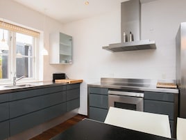 Una cocina moderna con horno empotrado, campana extractora de acero inoxidable y ventana con vistas al exterior.
