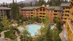 Un hôtel doté d’une piscine entourée d’arbres, avec une chaîne de montagnes en toile de fond.