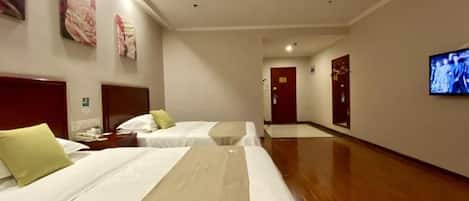 Habitación de hotel con dos camas, un televisor y un pasillo que lleva a una puerta.