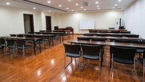Un salón de conferencias con varias mesas y sillas, una pizarra y un proyector.