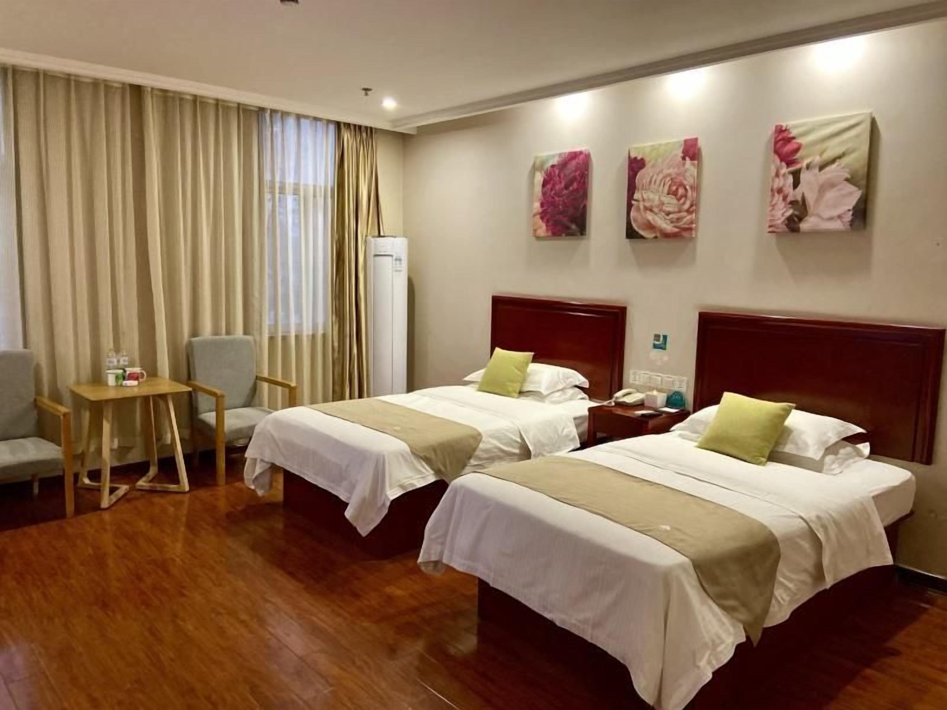 A hotel room with two beds, a desk, a chair, and a minibar.