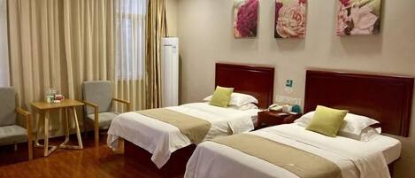 A hotel room with two beds, a desk, a chair, and a minibar.