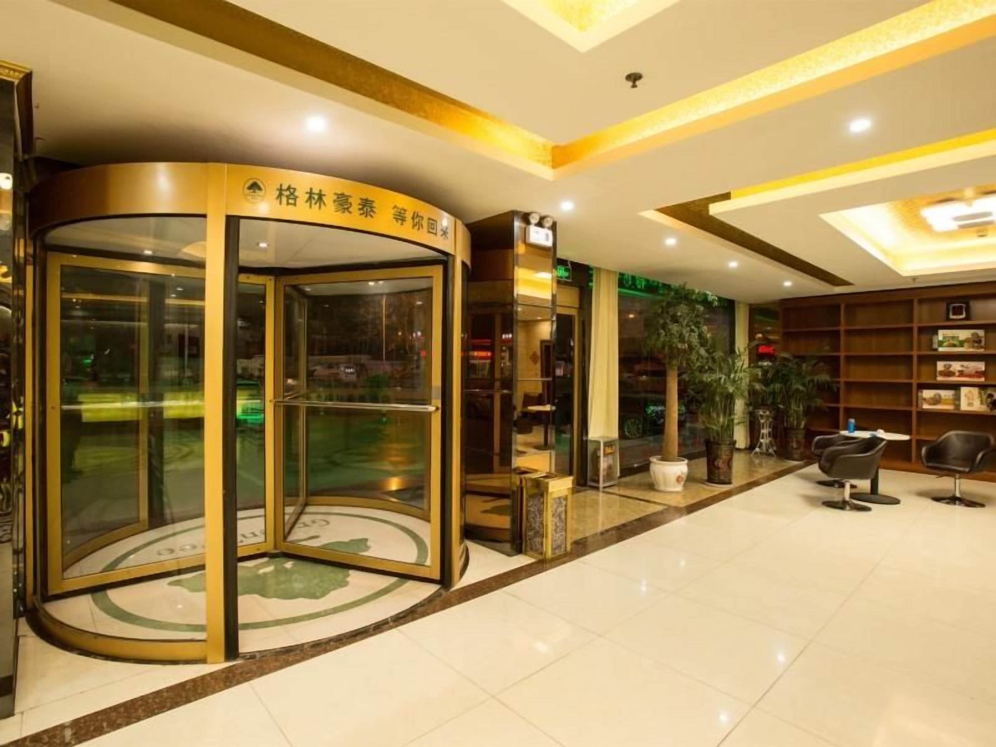 A hotel lobby with a revolving door, seating area, and a reception desk.