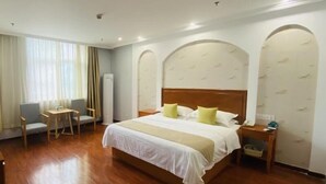Habitación de hotel con una cama grande, una mesita, una silla y una mesita de noche.