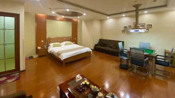 Una habitación de hotel con cama, sofá, escritorio y silla, y una mesa de centro.