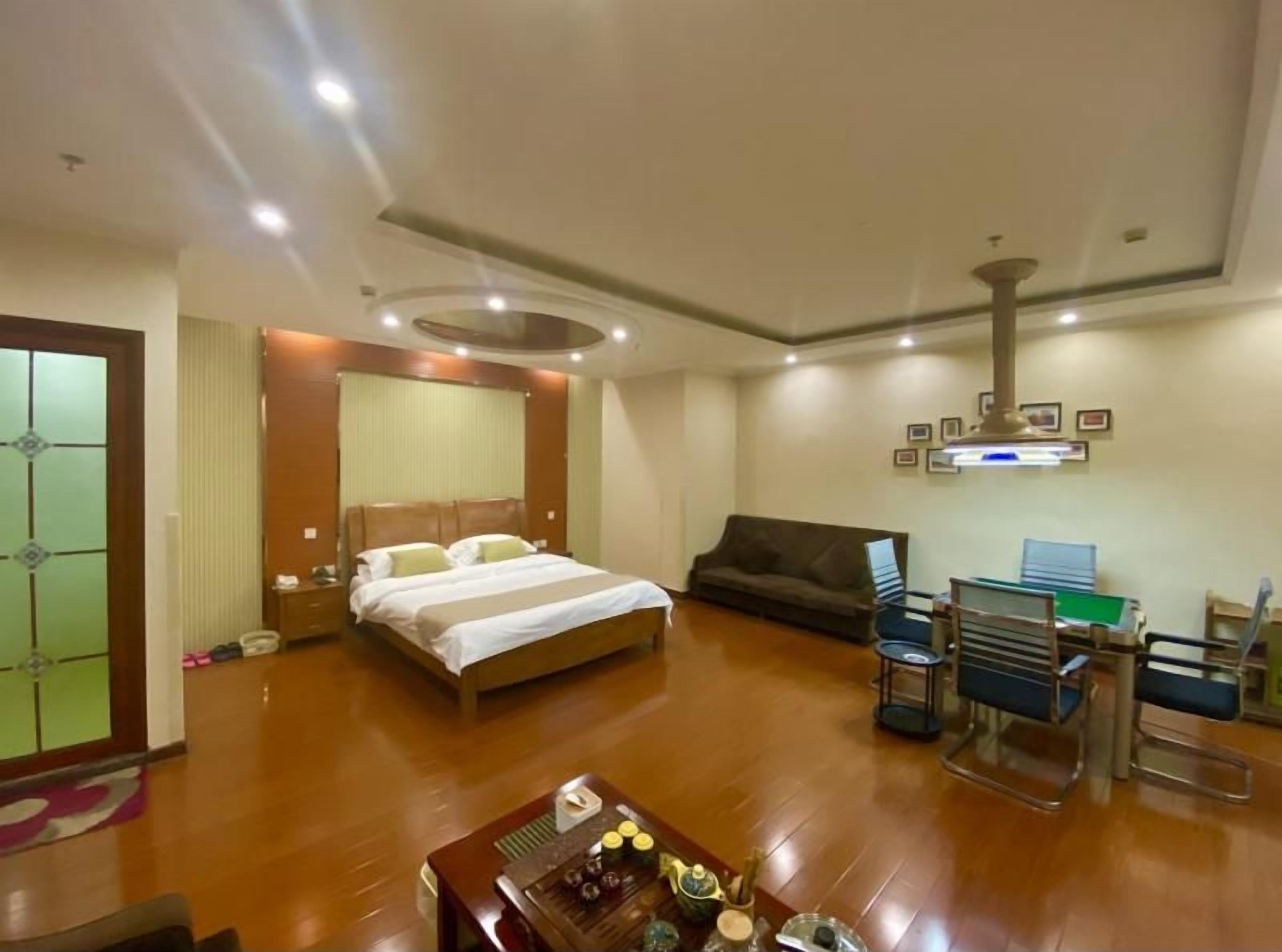A hotel room with a bed, a sofa, a desk with a chair, and a coffee table.