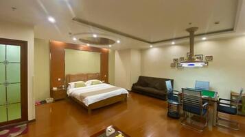A hotel room with a bed, a sofa, a desk with a chair, and a coffee table.