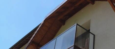 Un edificio moderno con balcón de madera y cielo despejado.
