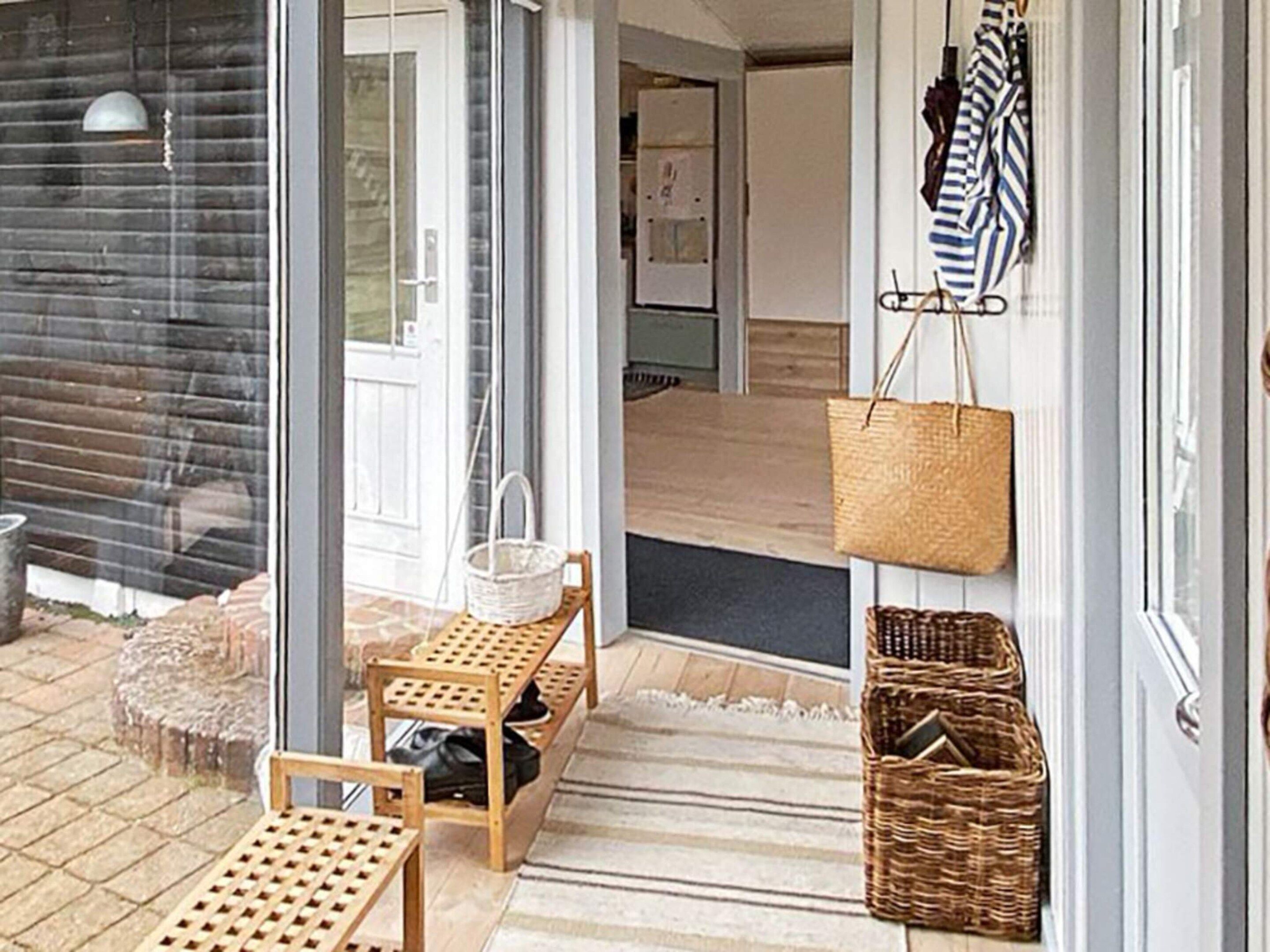 A wooden bench and a wicker basket near a glass door.